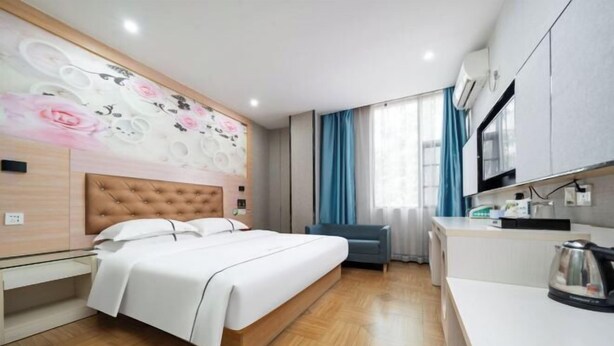 Una habitación de hotel moderna con una cama grande, una kitchenette y un detalle decorativo en la pared.