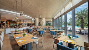 A spacious restaurant with high ceilings and large windows, offering views of the outdoors.