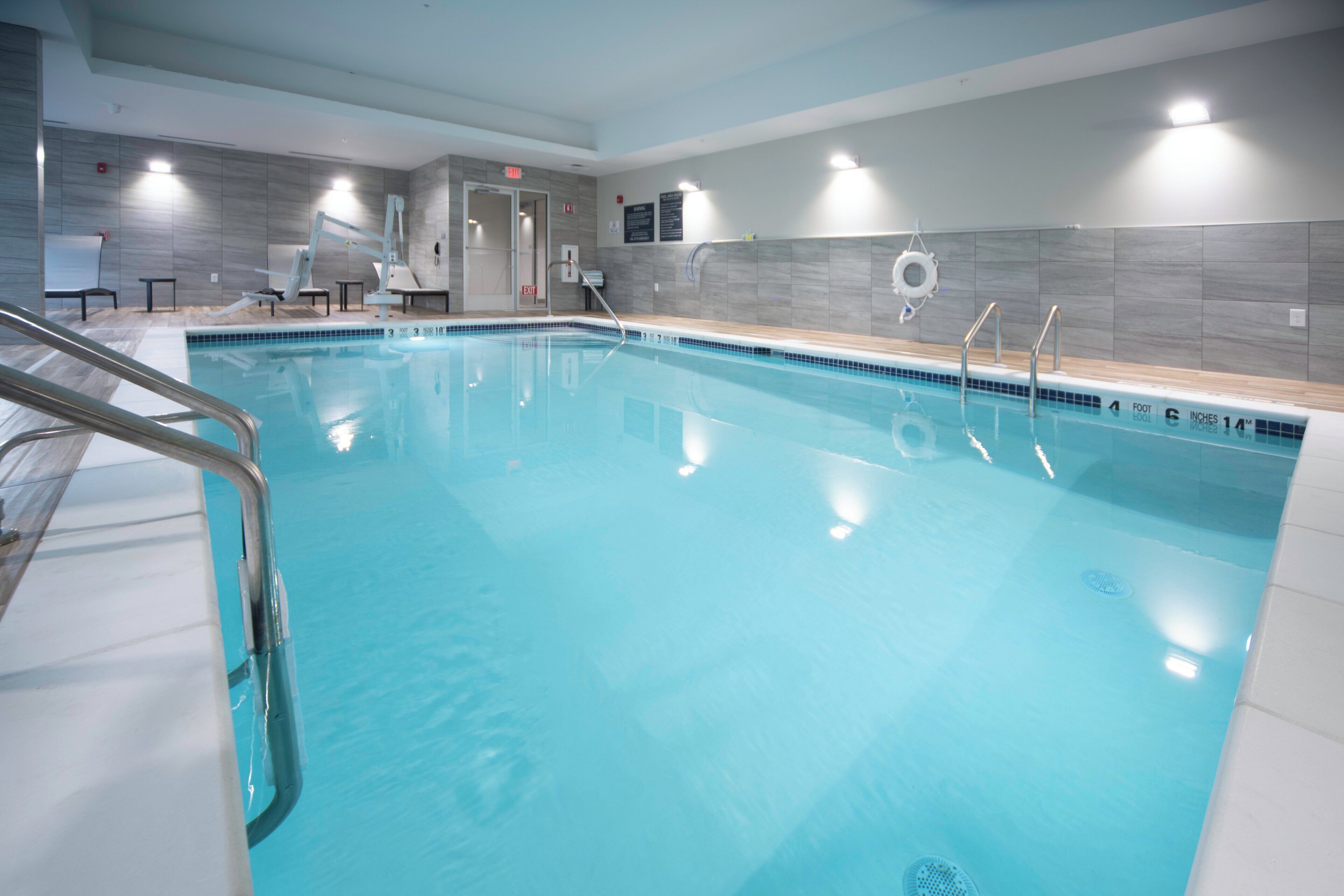 Une grande piscine intérieure à l’eau d’un bleu limpide, dotée d’un poste de surveillance pour les sauveteurs et d’un espace vestiaire.