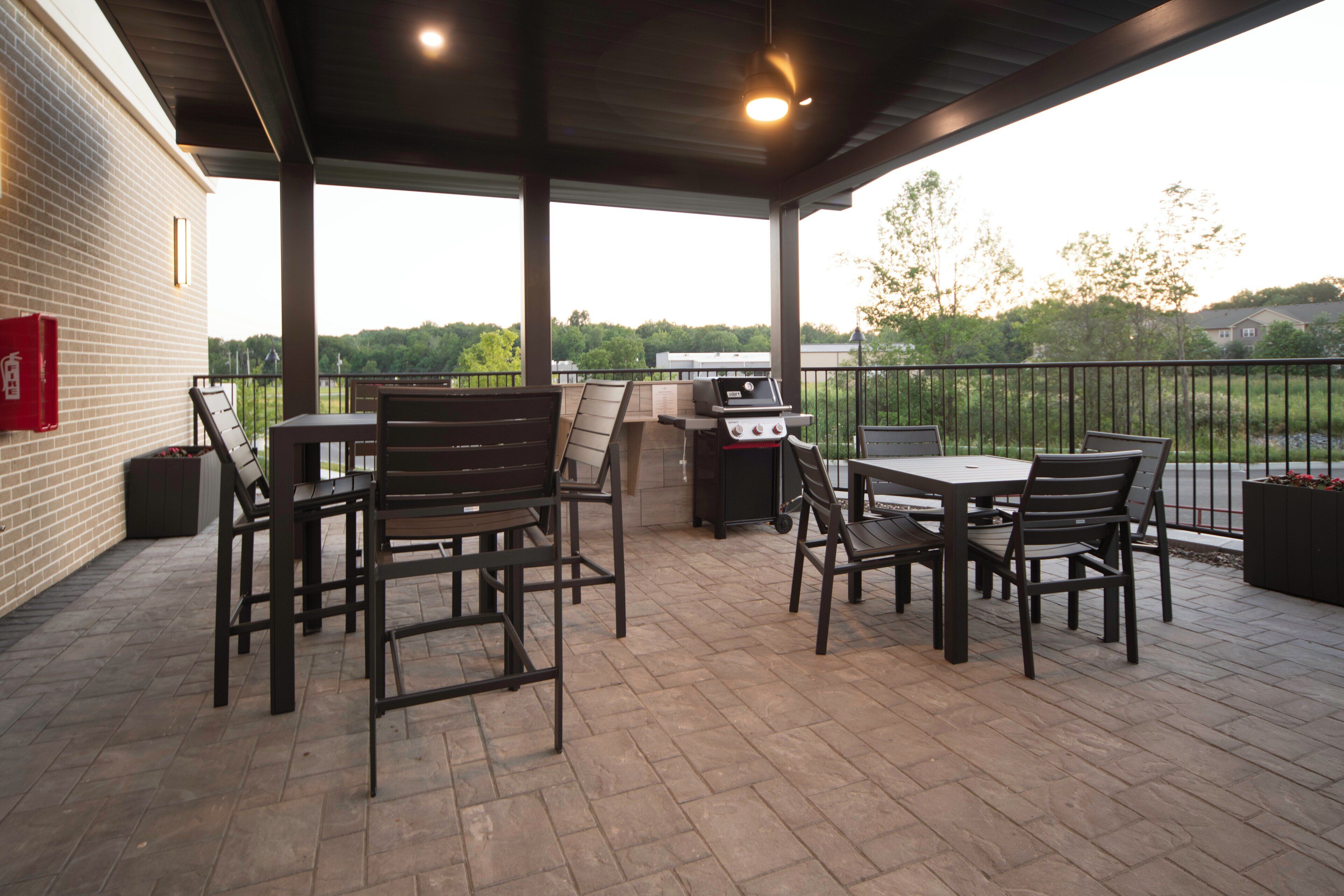 Une terrasse couverte, aménagée avec du mobilier d’extérieur, un barbecue et offrant une vue sur les environs.