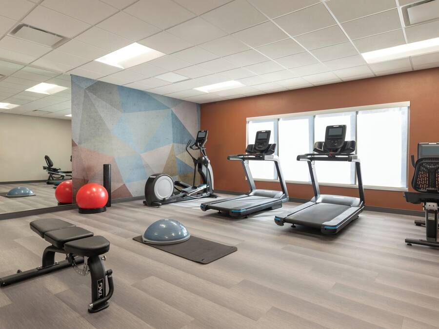 A gym with treadmills, elliptical machines, and exercise balls.