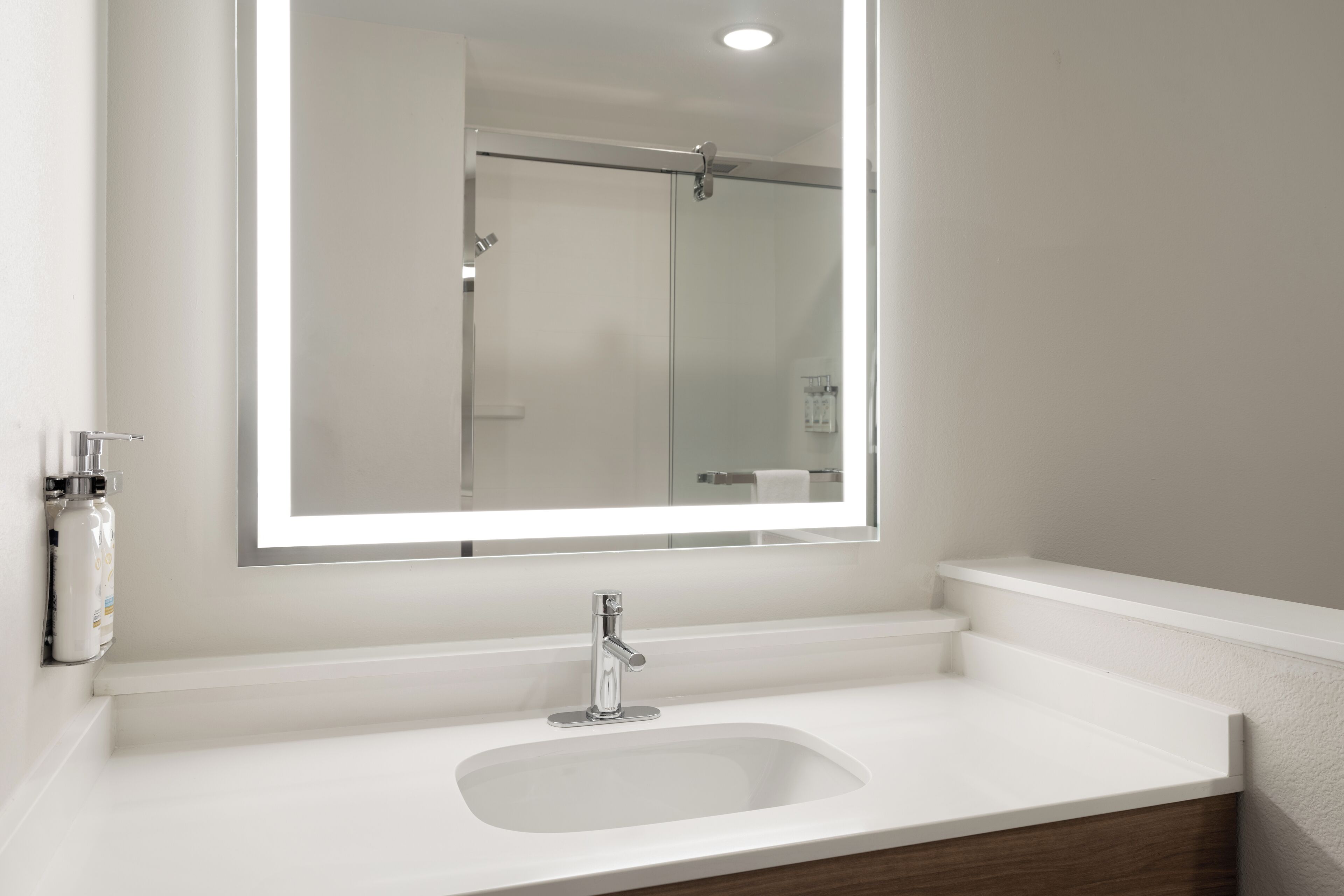 A bathroom with a white sink, a mirror, and a shower door.