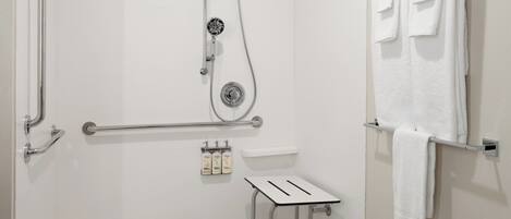 A modern bathroom with a shower, grab bars, a toilet, and a towel rack.