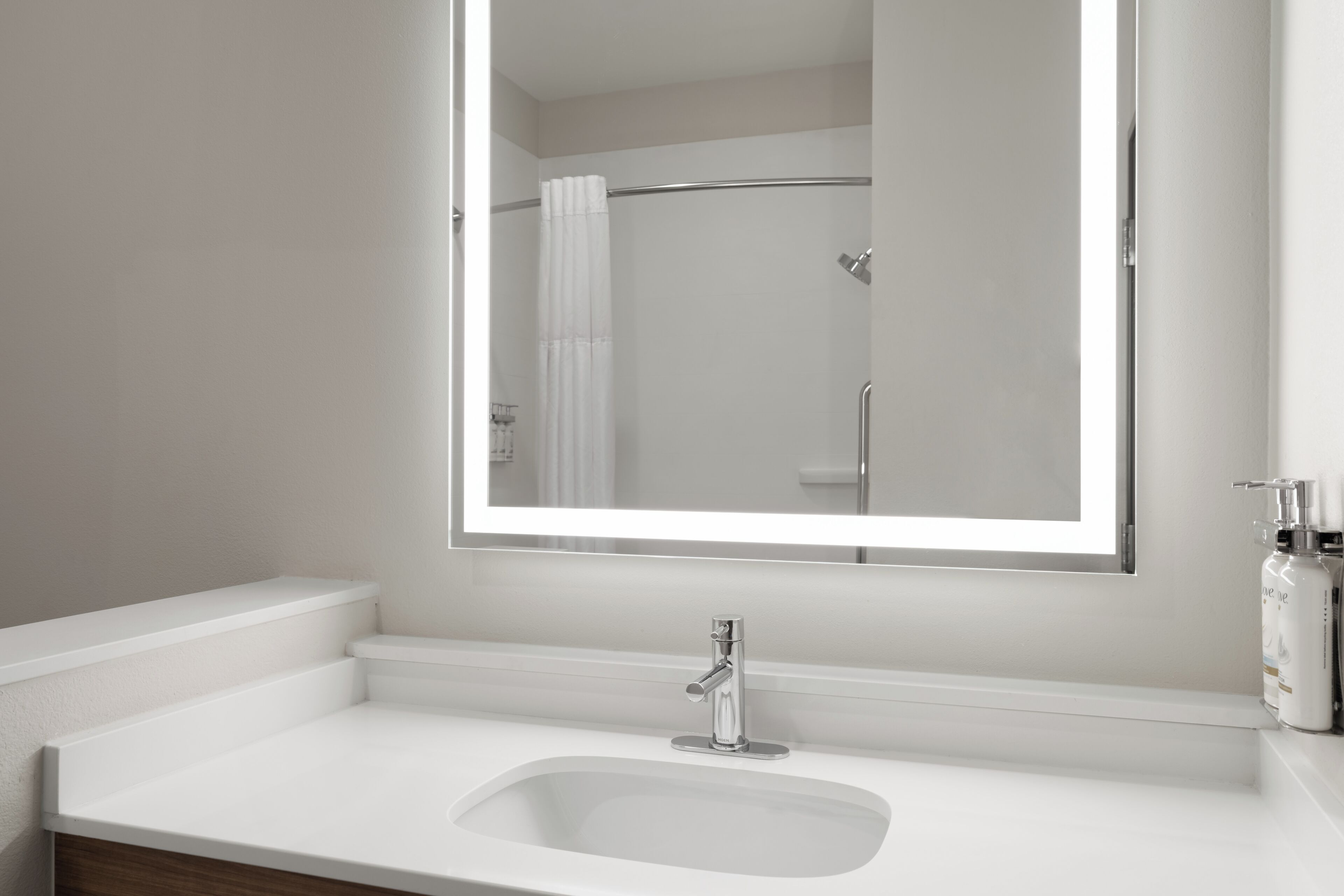 A bathroom with a white sink, a mirror, and a shower area.