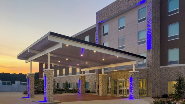 A modern hotel entrance with a covered walkway, stone pillars, and a glass door entrance. - Holiday Inn Express & Suites Meridian I 20 by IHG (Meridian)