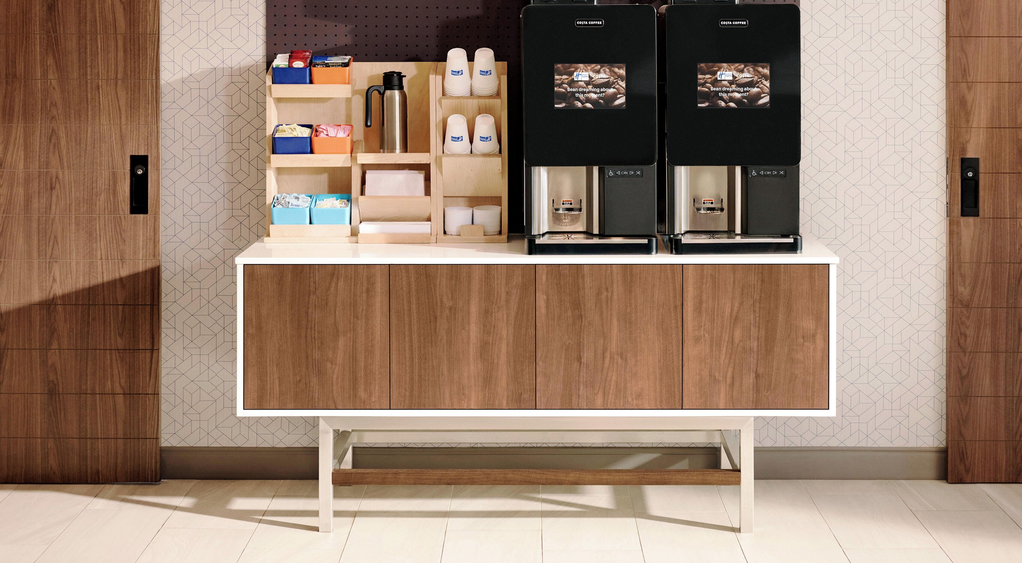 Un espace dédié au café, comprenant deux machines à café, une cafetière et divers accessoires liés au café, disposés sur des étagères.