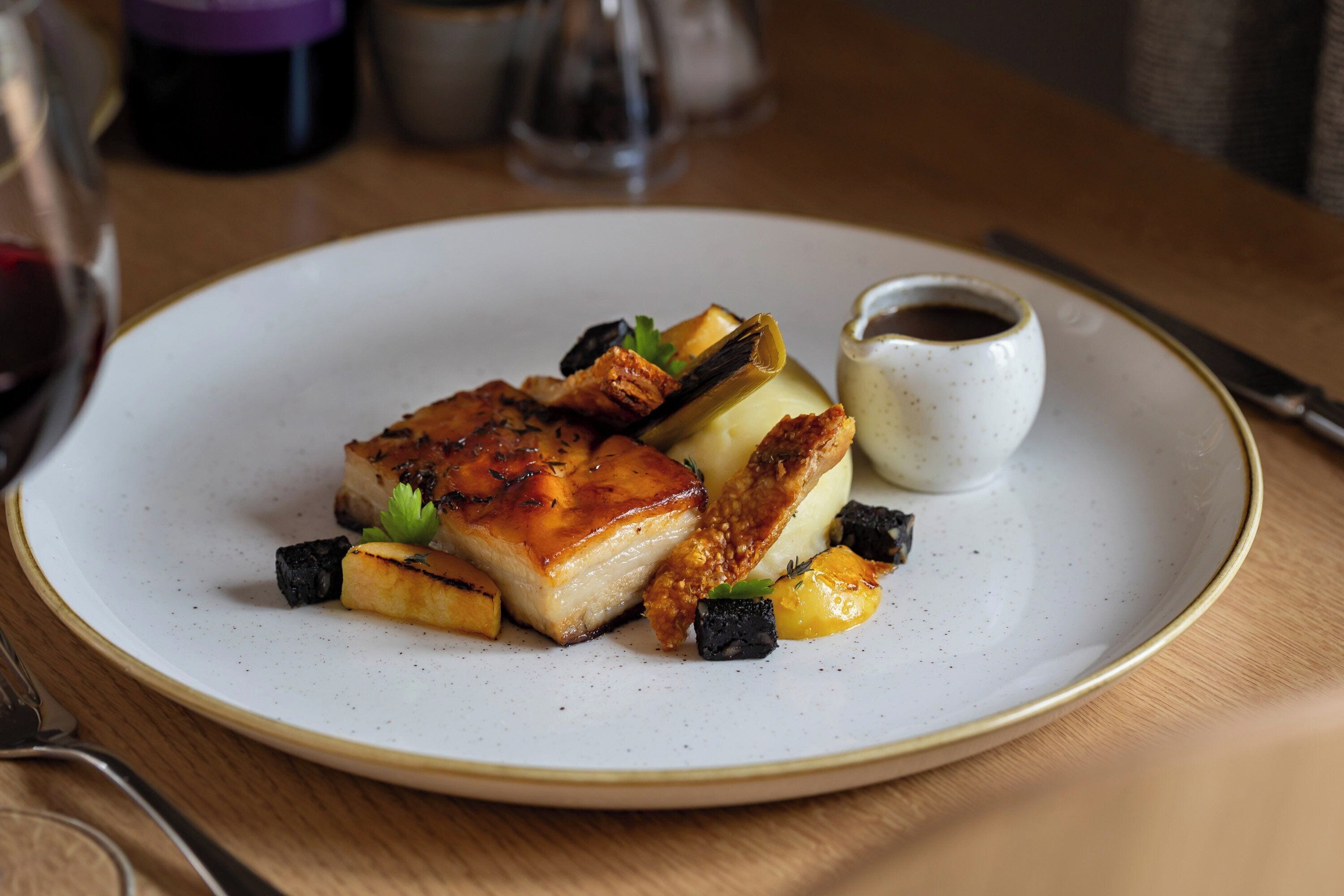 A plate of food with a small cup of sauce on a table.