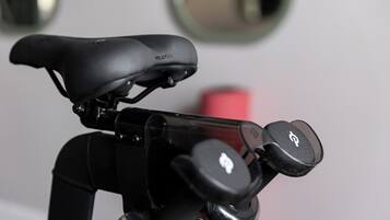 Ein Fahrrad mit schwarzem Sattel, beschriftet mit „PELOTON“, und einem Lenker mit einem Logo.