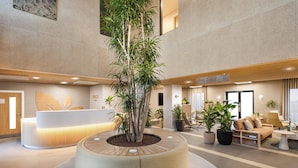 A modern lobby with a central circular planter, a reception desk, seating area, and a large window. - voco Zeal Exeter Science Park by IHG (Exeter)