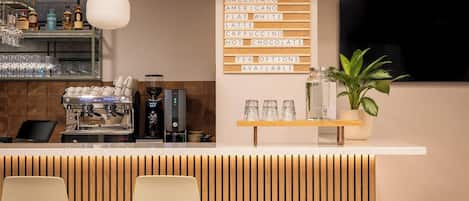 Zona de bar moderna con cafetera, opciones de espresso y asientos.