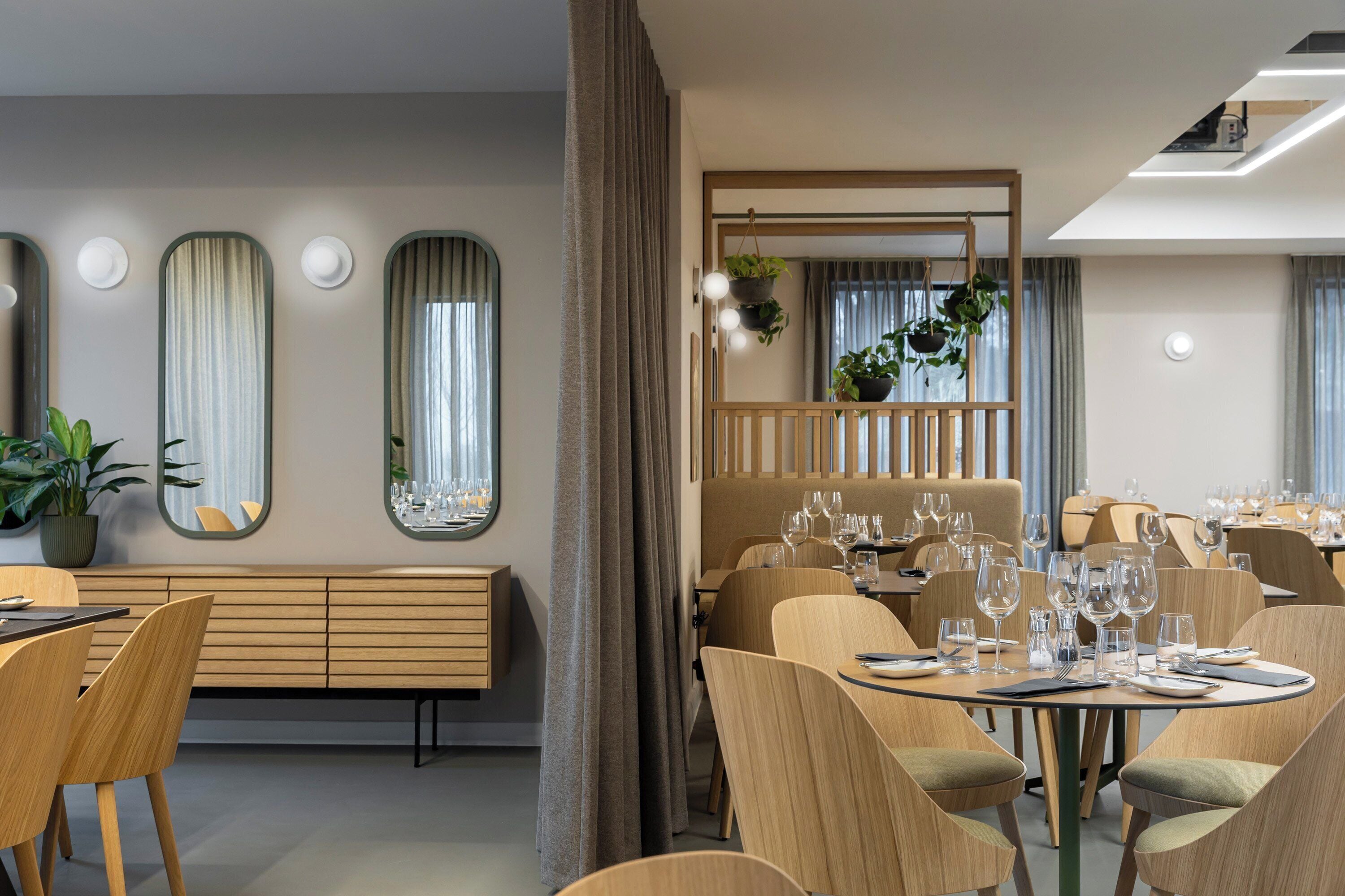 A modern dining area with round tables, wooden chairs, and a central seating area with a bench.