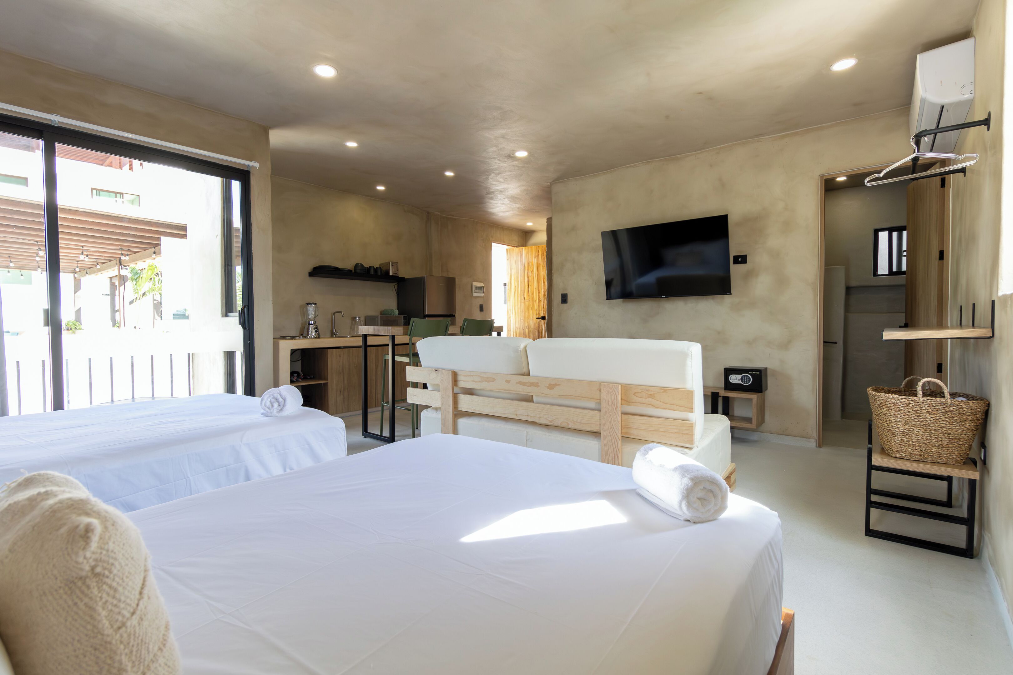 Une chambre d’hôtel moderne avec deux lits, une kitchenette, une télévision et un balcon.