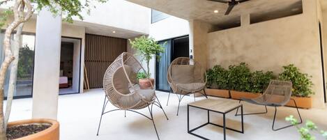 A modern outdoor seating area with wicker chairs, a wooden table, and potted plants.