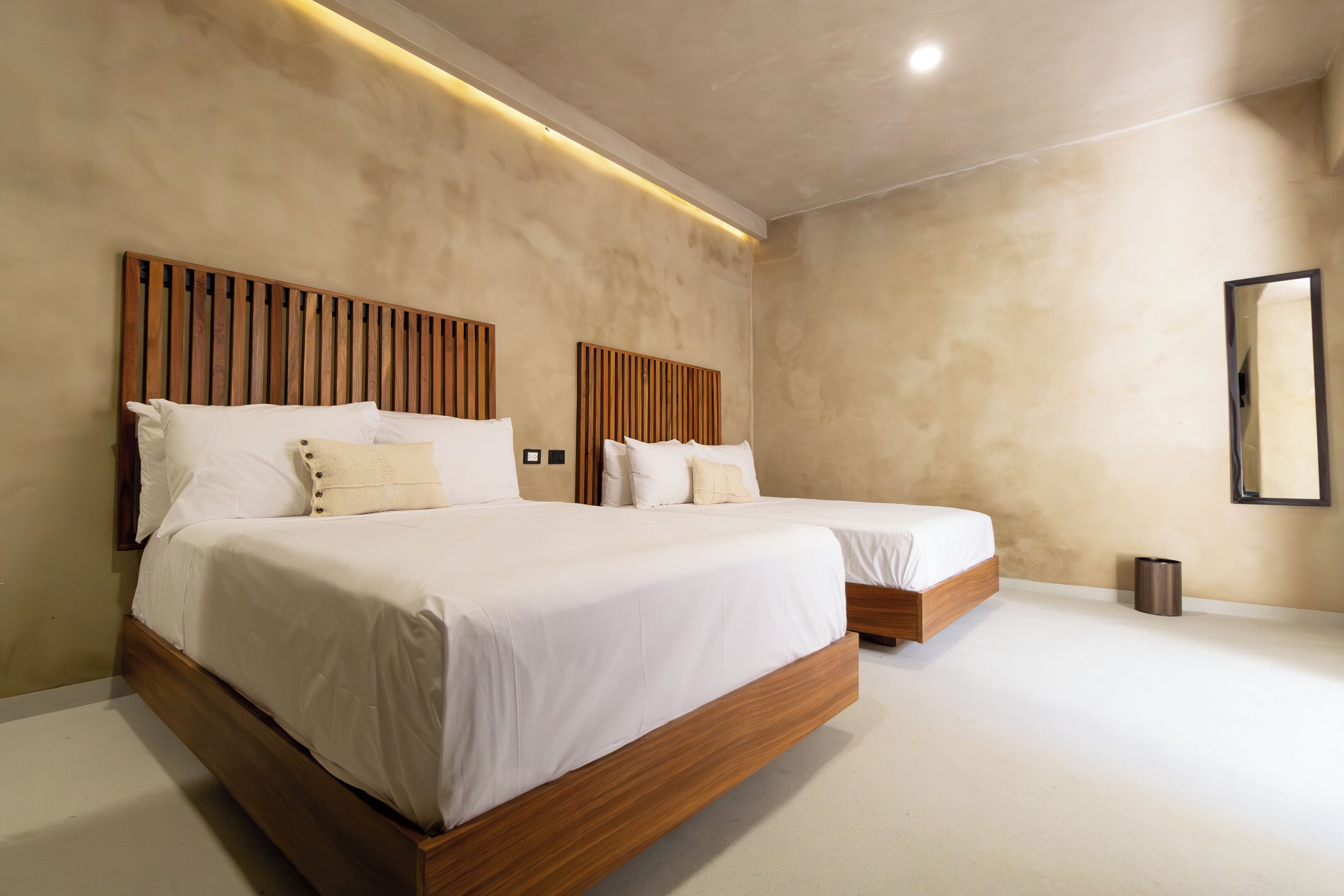 Una habitación de hotel moderna con dos camas, cabeceros de madera y un diseño minimalista.