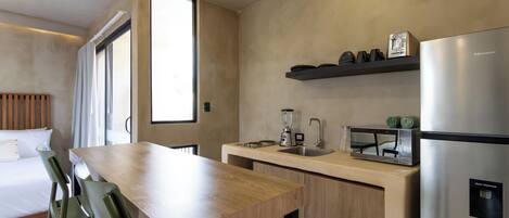 A modern kitchen with a wooden table, bar stools, a built-in oven, and a water dispenser.