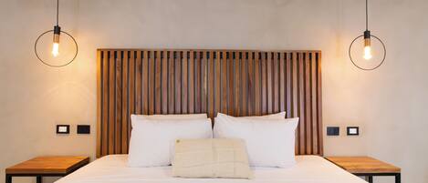 A neatly made bed with white linens, two bedside tables, and a wooden headboard with vertical slats.