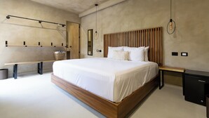 Ein modernes Schlafzimmer mit einem großen Bett, einem Holz-Kopfteil, Nachttischen, einer Bank und einem kleinen schwarzen Schrank.