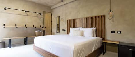 Un dormitorio moderno con una cama grande, cabecera de madera, mesitas de noche, un banco y un mueble negro pequeño.