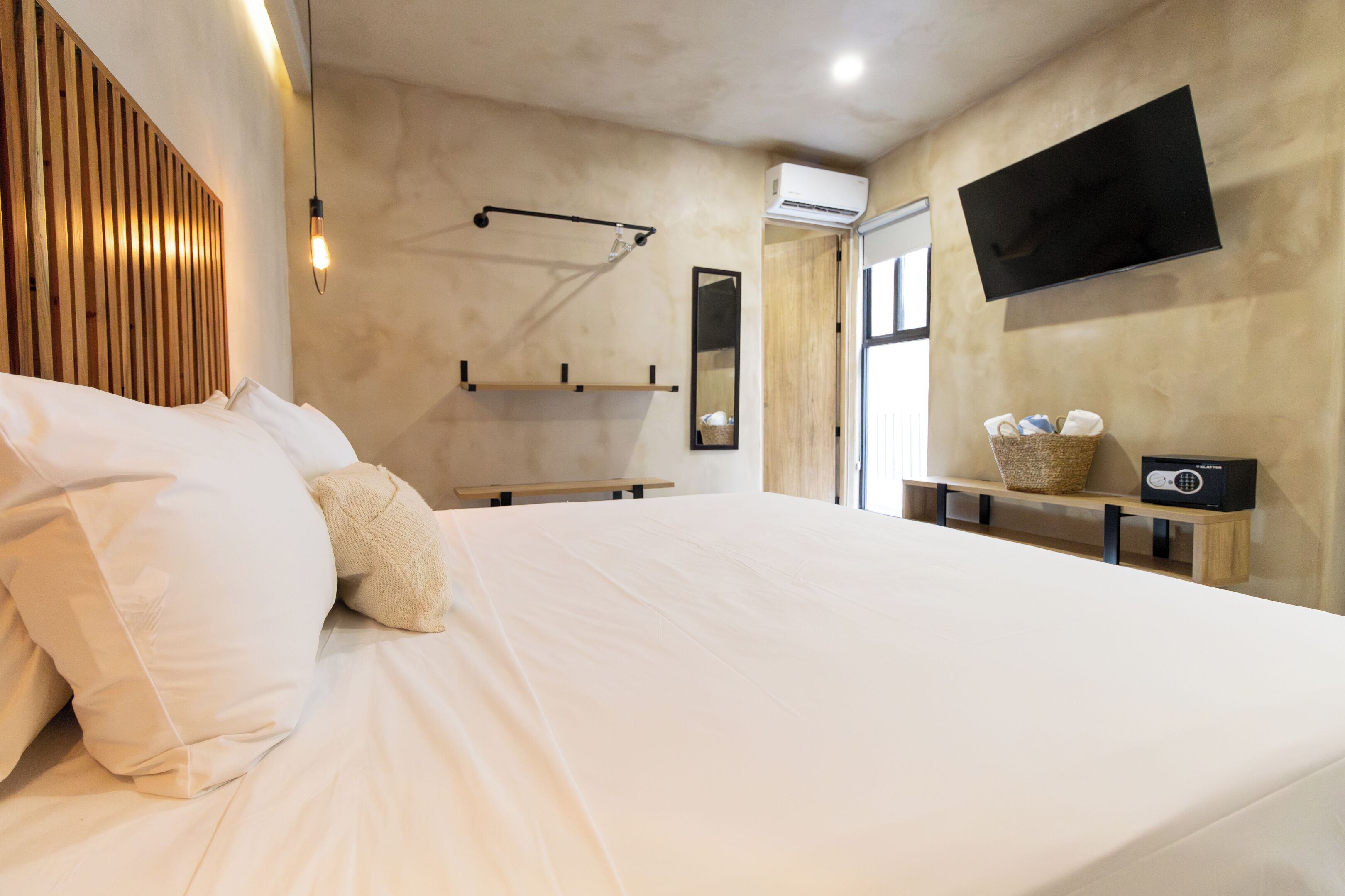 A modern bedroom with a large bed, a mounted TV, and a wooden headboard.
