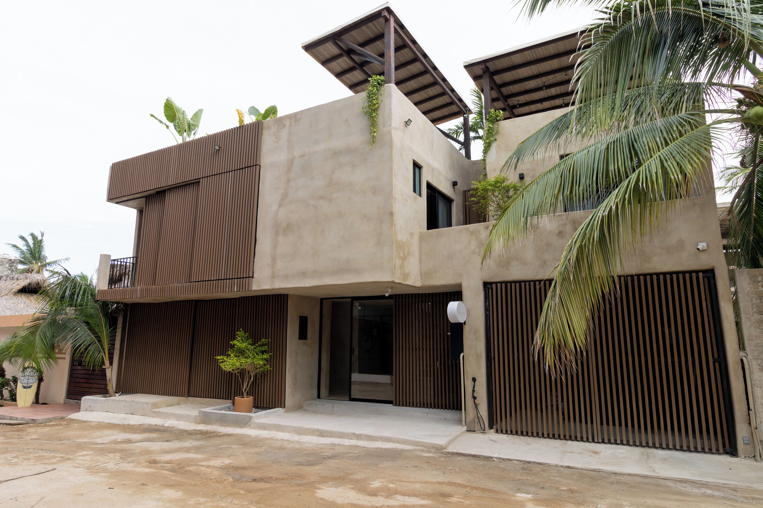 A modern two-story house with a flat roof, large windows, and a concrete facade.