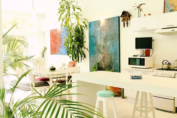 A bright kitchen with white cabinets, a microwave, a gas stove, and a hanging plant. - Fascinating loft with heated Swimming pool (Oaxaca de Juárez)