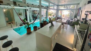 A spacious indoor area with a pool, potted plants, and a dining area with chairs and a table. - Two story high ceiling loft with heated pool (Oaxaca de Juárez)