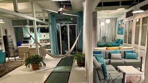 A modern living room with a hammock, a sofa set, and a dining area. - Two story high ceiling loft with heated pool (Oaxaca de Juárez)