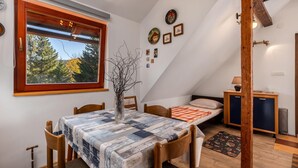 A cozy room with a dining table, chairs, a bed, a small desk, and a window with a view of trees. - Awesome apartment in Ravna Gora with WiFi (Ravna Gora)