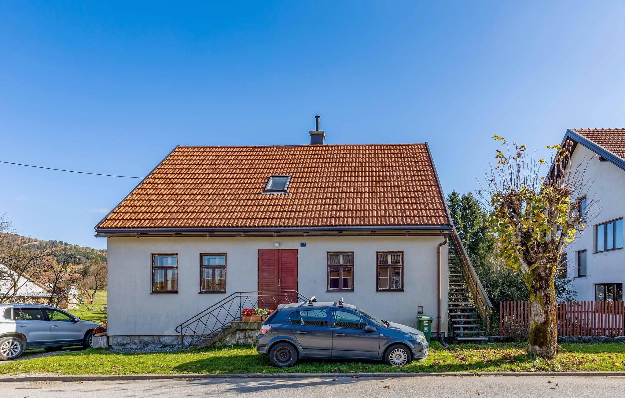 A two-story house with a red-tiled roof, a front door, and a small window.