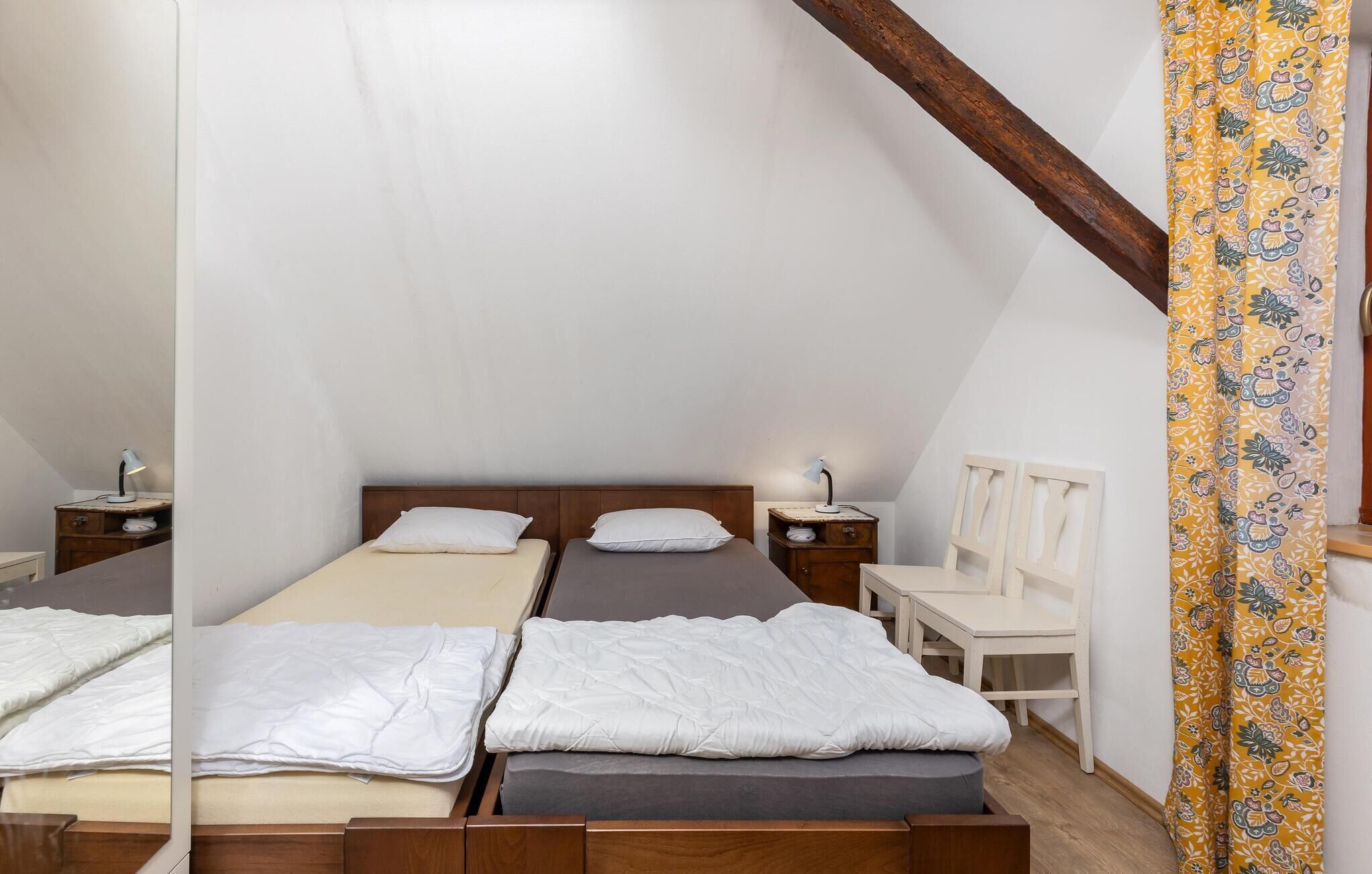 Une chambre avec deux lits, des têtes de lit en bois, des tables de chevet avec des lampes, un petit bureau et une chaise.