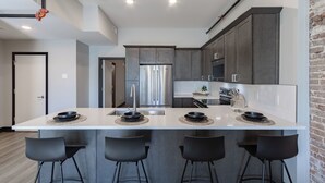 A modern kitchen with a central island, stainless steel appliances, and dark cabinetry.