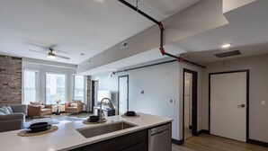 A modern kitchen with a central island, built-in dishwasher, and a ceiling fan.