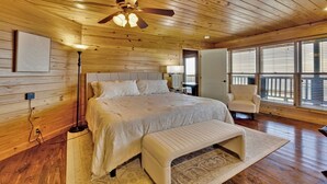 A spacious bedroom with a large bed, a bench, a chair, and a ceiling fan. - The Lodge in Mentone.  (Mentone)