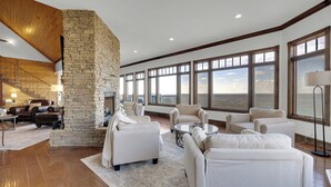 A spacious living room with a stone fireplace, large windows, and a wooden ceiling. - The Lodge in Mentone.  (Mentone)