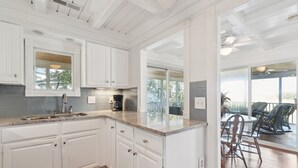 A kitchen with white cabinets, a granite countertop, and a view to an outdoor patio area.