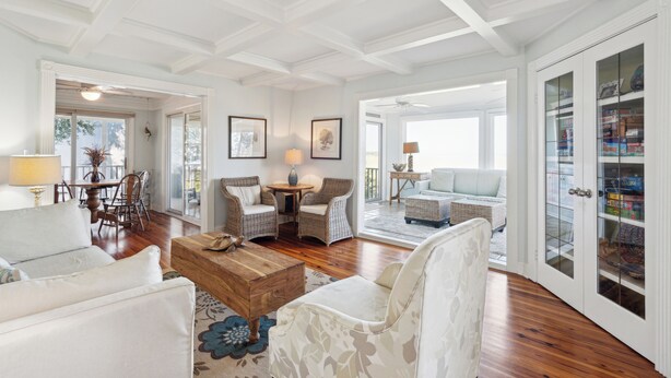 A spacious living room with a high ceiling, hardwood floors, and a large glass-fronted cabinet.