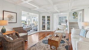 A spacious living room with wicker furniture, a wooden coffee table, and a patterned rug.