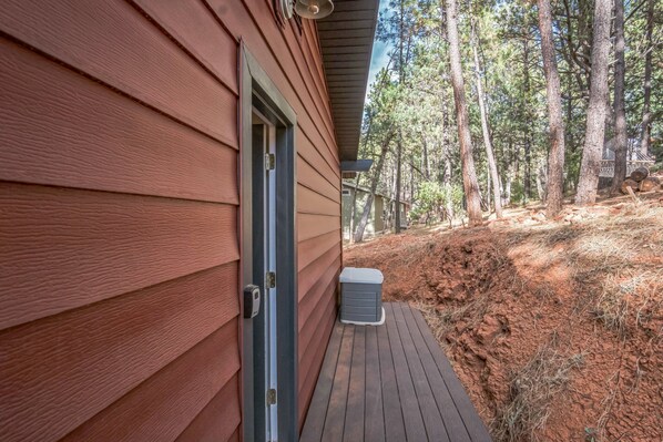 A wooden exterior of a building with a door and a small air conditioning unit on a wooden deck.