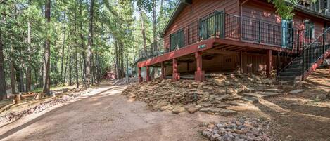 Une cabane avec une façade en bois, un balcon et un escalier menant à l’étage supérieur.