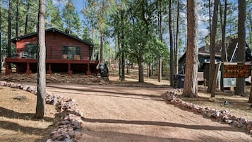 Eine rustikale Holzhütte mit Veranda, umgeben von einem Wald.
