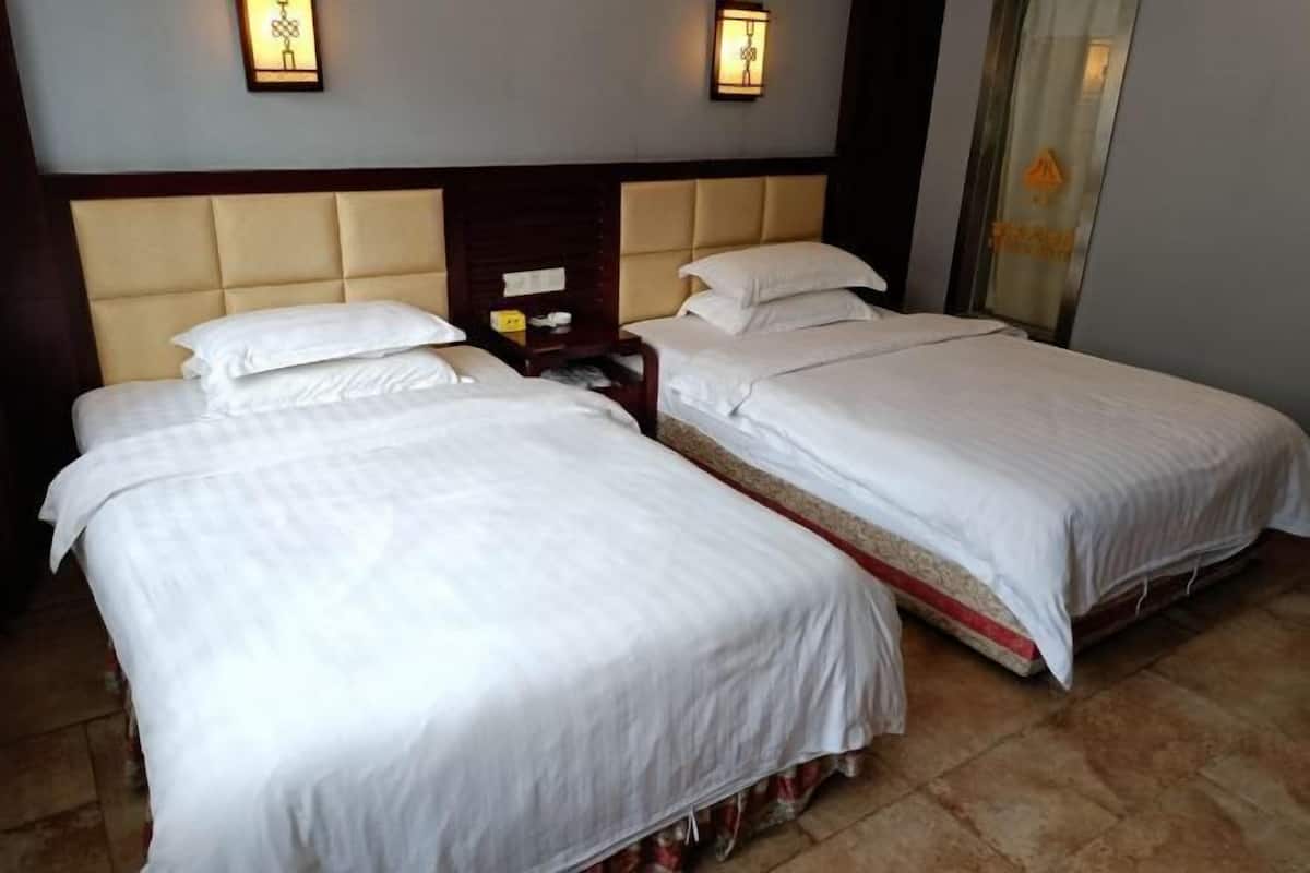 Una habitación de hotel con dos camas, cabecero de madera y lámparas fijadas a la pared.