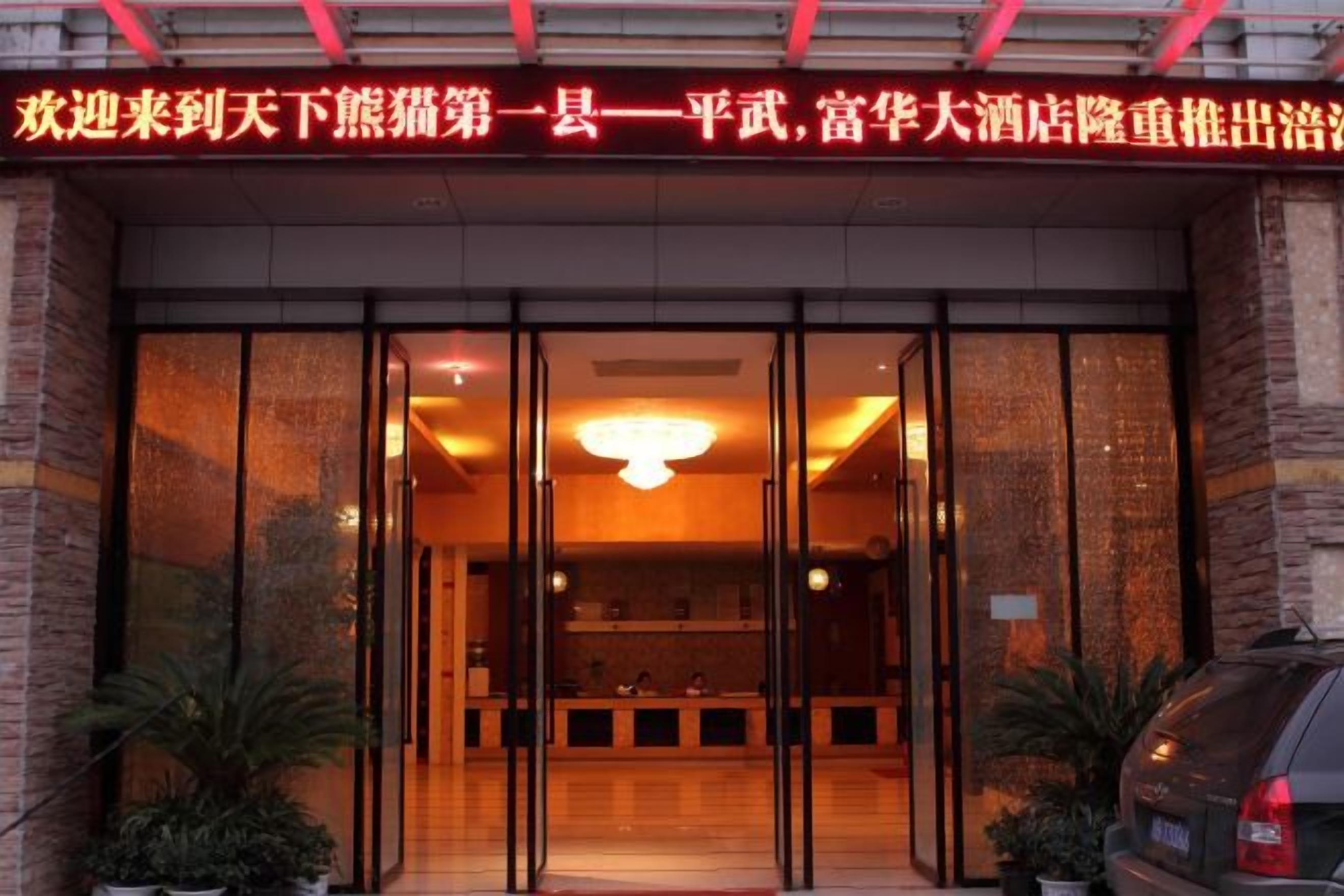 A hotel entrance with a reception desk, glass doors, and a sign above.