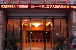 A hotel entrance with a reception desk, glass doors, and a sign above. - Fuhua Hotel (Pingwu)