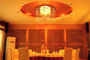 Un'area pranzo con un lampadario, un tavolo apparecchiato per due e una parete decorata.