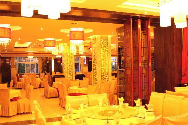 A banquet hall with round tables, chairs, and chandeliers.