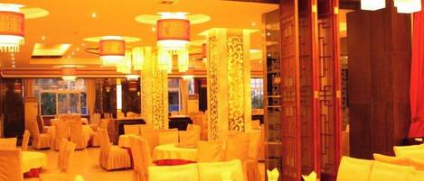A banquet hall with round tables, chairs, and chandeliers.