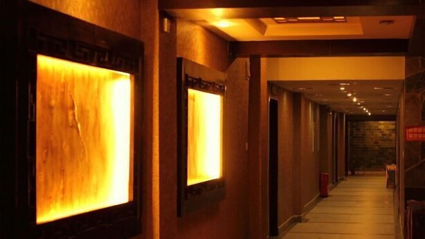 A hallway with wooden walls and a warm, illuminated wall feature. - Fuhua Hotel (Pingwu)