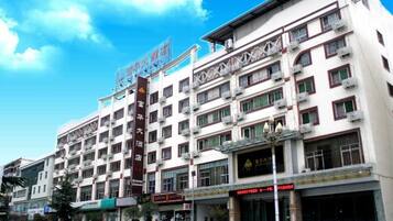 A multi-story hotel with a prominent sign, balconies, and storefronts on the ground floor.