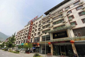 A multi-story hotel with a prominent red sign, multiple balconies, and a storefront with signage. - Fuhua Hotel (Pingwu)