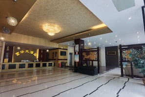 A hotel lobby with a reception desk, a staircase, and a large plant. - Fuhua Hotel (Pingwu)